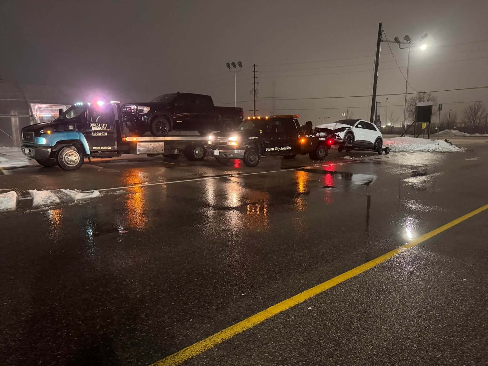 Forest City Roadside flatbed and wrecker tow trucks working at night in London Ontario