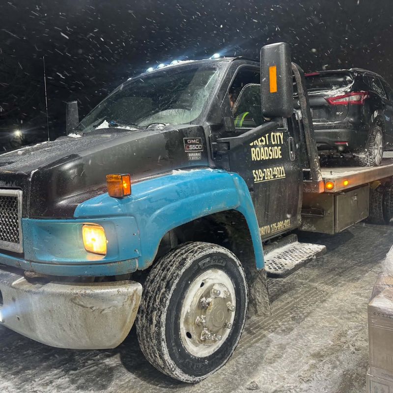 Forest City Roadside GMC C5500 flatbed in a snowstorm at night