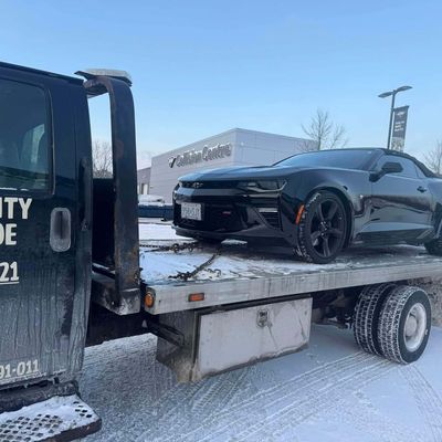 Black Camaro on a flatbed outside a collision centre in winter