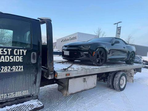 Black Chevrolet Camaro on a Forest City Roadside flatbed outside a collision centre in winter