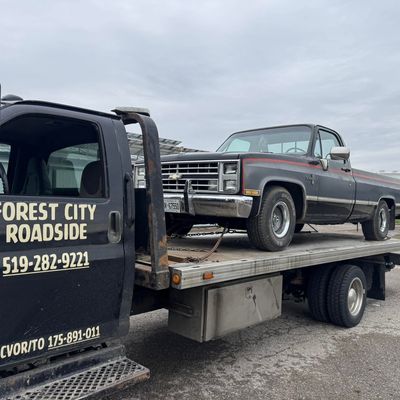 Classic Chevy Silverado pickup on a flatbed tow truck