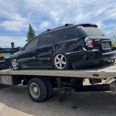 Collision-damaged Subaru on a flatbed tow truck