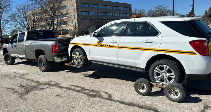 Forest City Roadside pickup wrecker towing a white SUV on wheel dollies